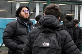 Tawheed, an English teacher, stands outside speaking with students.