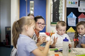 primary school teacher in class helping her pupils