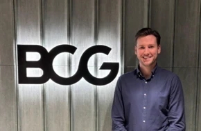 Patrick, a Summer Project participant, standing in front of a BCG logo, smiling.
