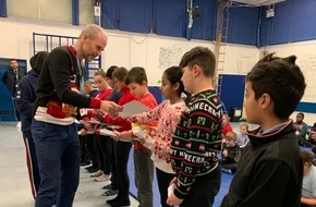 Headteacher gives out paper to students lining up